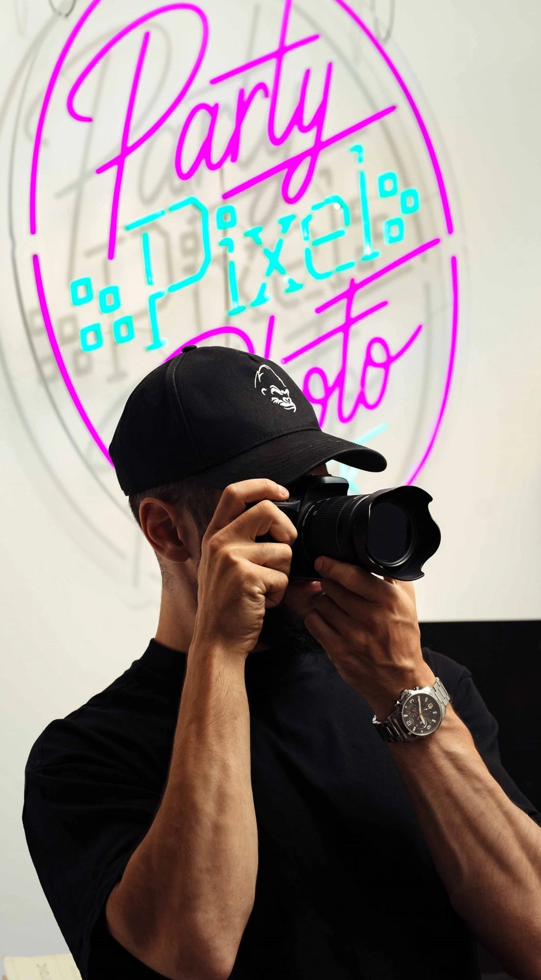 Albert Arsene, founder and lead photographer at Party Pixel Photography, shooting in front of the neon studio signage
